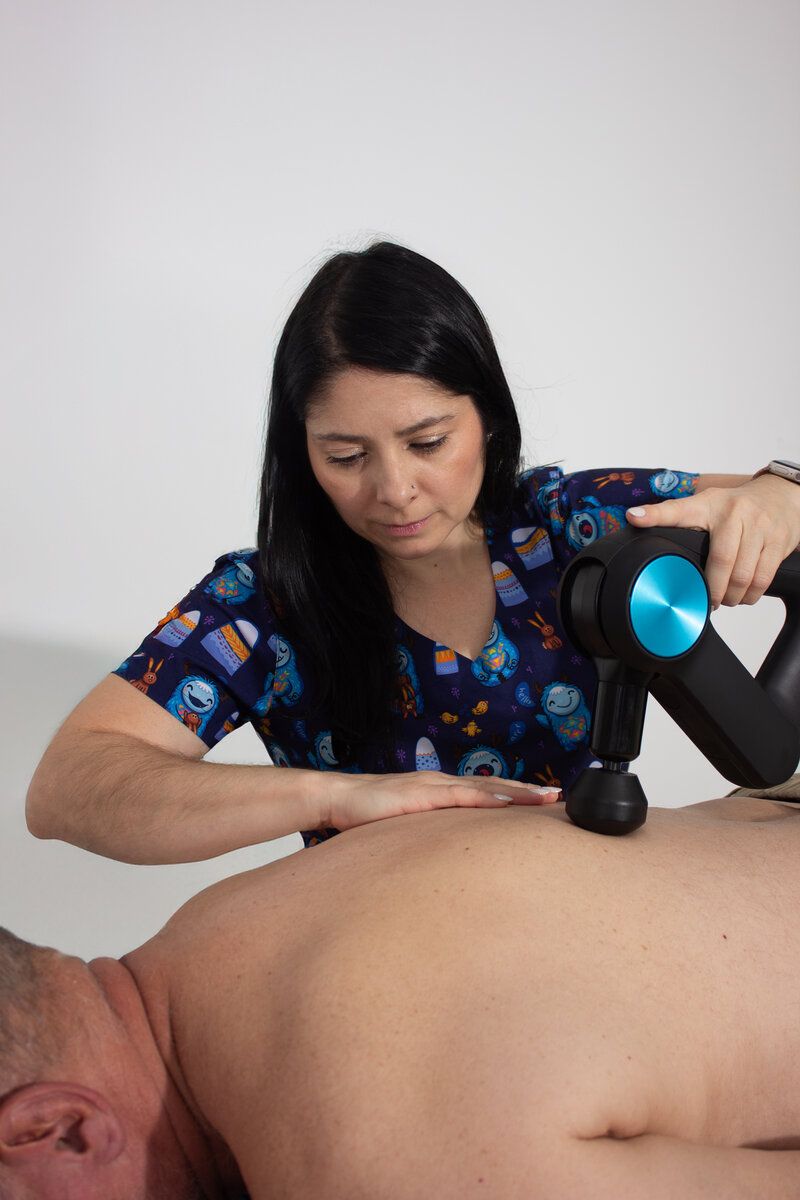 Close-up of percussion therapy being applied to a patient's back